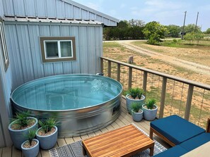 Ein Whirlpool auf einer Terrasse mit Topfpflanzen und einem Holztisch.