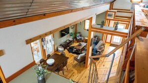 Ein mehrstöckiger Innenraum aus Holz mit Essbereich, Sitzgelegenheiten und einer Treppe.