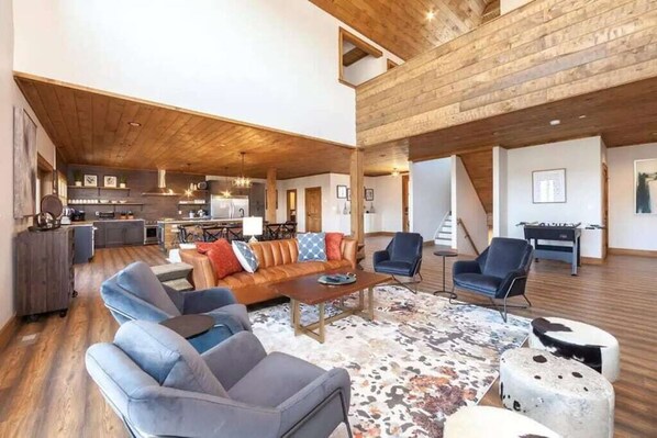 A spacious living area with a wooden ceiling, a sofa set, a coffee table, and a rug.