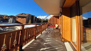 A wooden balcony with a view of snow-covered mountains and buildings. - Charming T3 in a residence close to the slopes and shops South-facing balcony (La joue du loup)