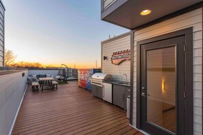 Una terraza con piso de madera, una parrilla y un área de estar con mesa y sillas.