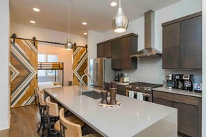 A modern kitchen with a central island, stainless steel appliances, and a stylish pendant light. - Wild Horse by Avantstay Gorgeous Nashville Townhouse w/ Rooftop Patio & Outdoor Kitchen (Nashville)