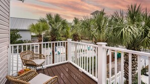 Une terrasse en bois avec des balustrades blanches, des chaises en osier et une table.