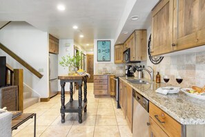 Eine Küche mit Holzausstattung, einer Arbeitsplatte aus Granit, einer Uhr und einem Essbereich mit Tisch und Stühlen.
