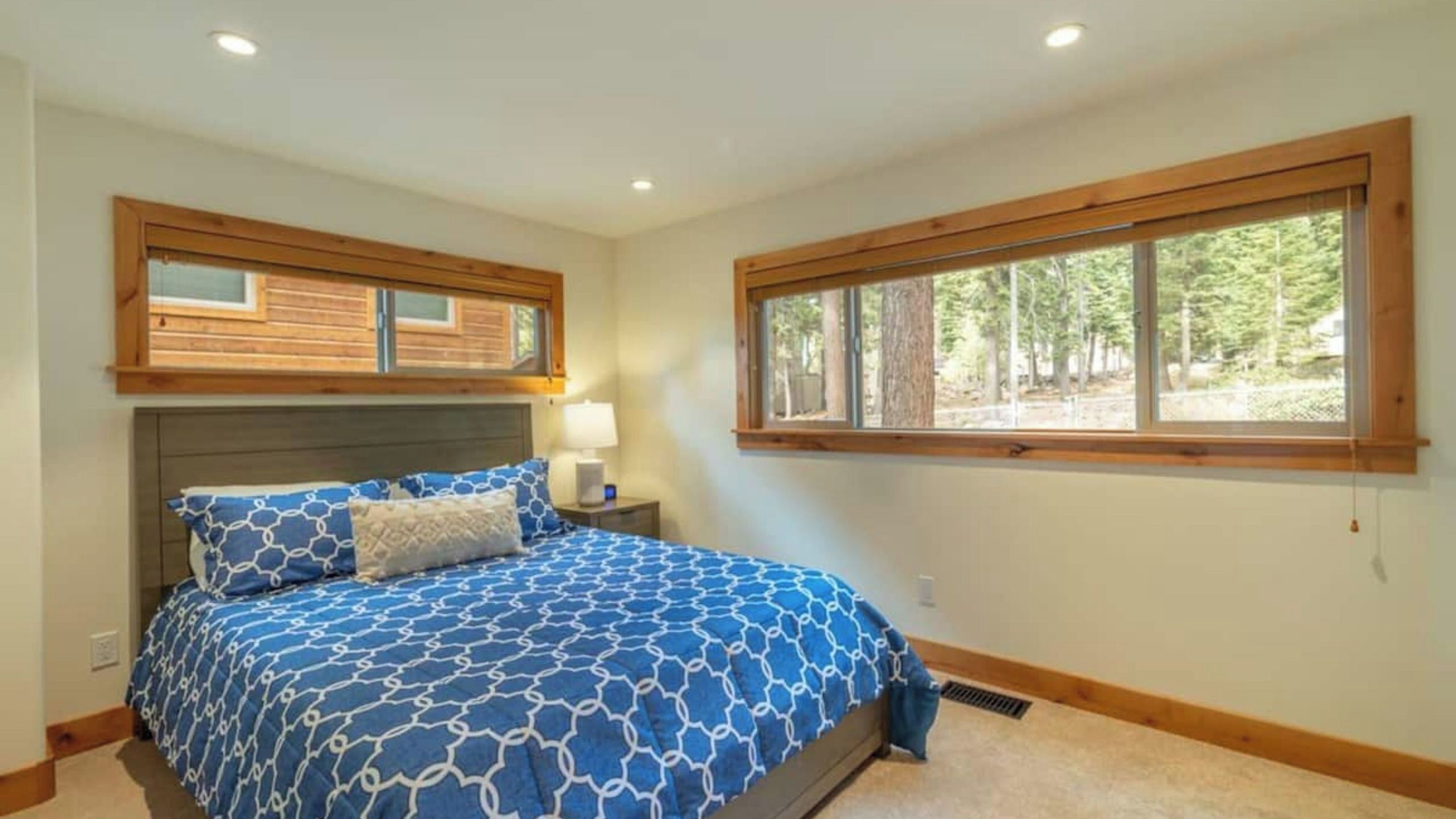 A bedroom with a bed, a nightstand, a window, and a headboard.