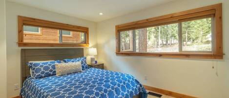 A bedroom with a bed, a nightstand, a window, and a headboard.