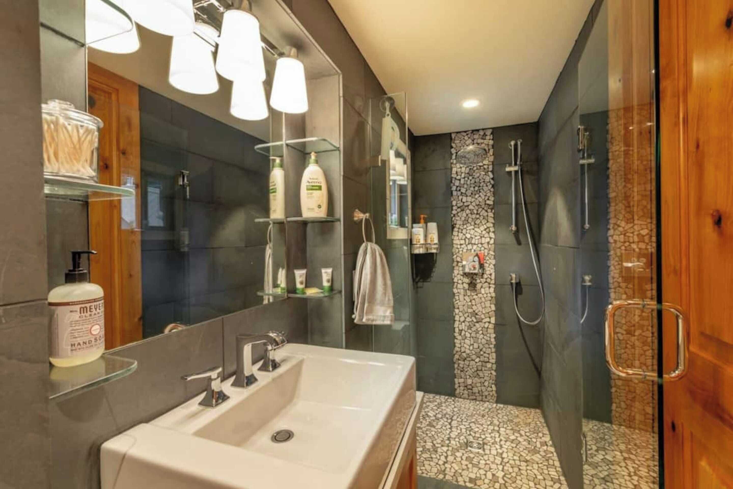 Een moderne badkamer met een groot wastafel, spiegel en een douchecabine van glas.