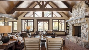A spacious living room with a stone fireplace, leather sofas, and a high wooden ceiling with skylights. - Big Pine by Avantstay Stunning Secluded Oregon Home w/ Hot Tub (Bend)