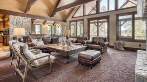 A spacious living room with a high ceiling, stone walls, and large windows. - Big Pine by Avantstay Stunning Secluded Oregon Home w/ Hot Tub (Bend)