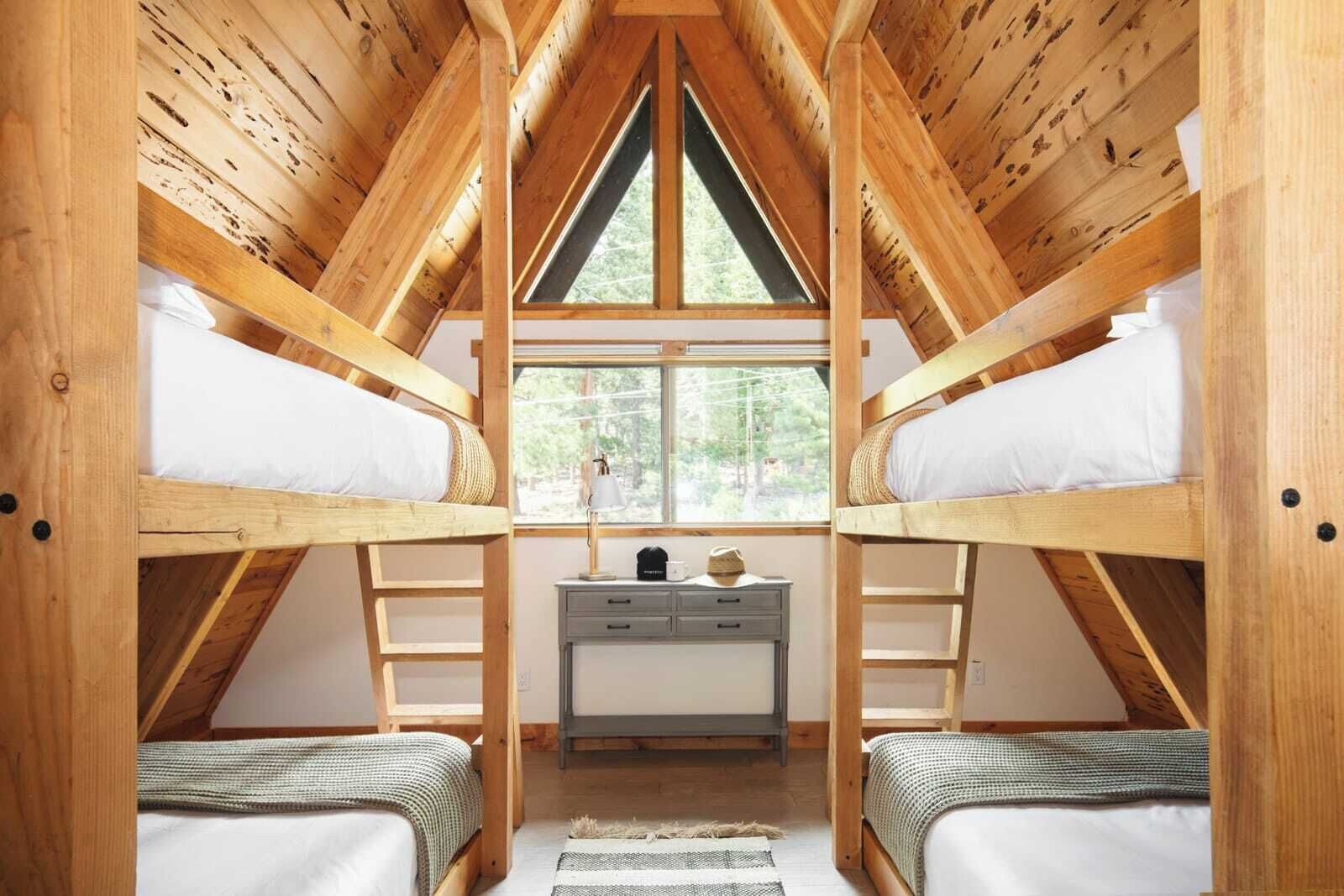 Un dormitorio estilo ático con dos literas, un escritorio y una ventana.