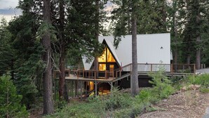 A cabin with a wooden deck, surrounded by trees. - Timberline by Avantstay Stunning Chalet Cabin w/ Hot Tub, Pool Table & Home Theater! (Carnelian Bay)