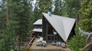 A modern cabin with a large deck, surrounded by dense forest. - Timberline by Avantstay Stunning Chalet Cabin w/ Hot Tub, Pool Table & Home Theater! (Carnelian Bay)
