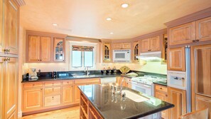 A spacious kitchen with wooden cabinets, a central island, a microwave, and a stove.