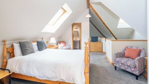 Een slaapkamer met een houten bed, een fauteuil met patroon en een dakvenster.