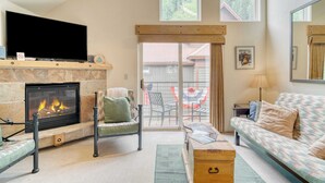 A living room with a fireplace, a sofa, a chair, and a television.