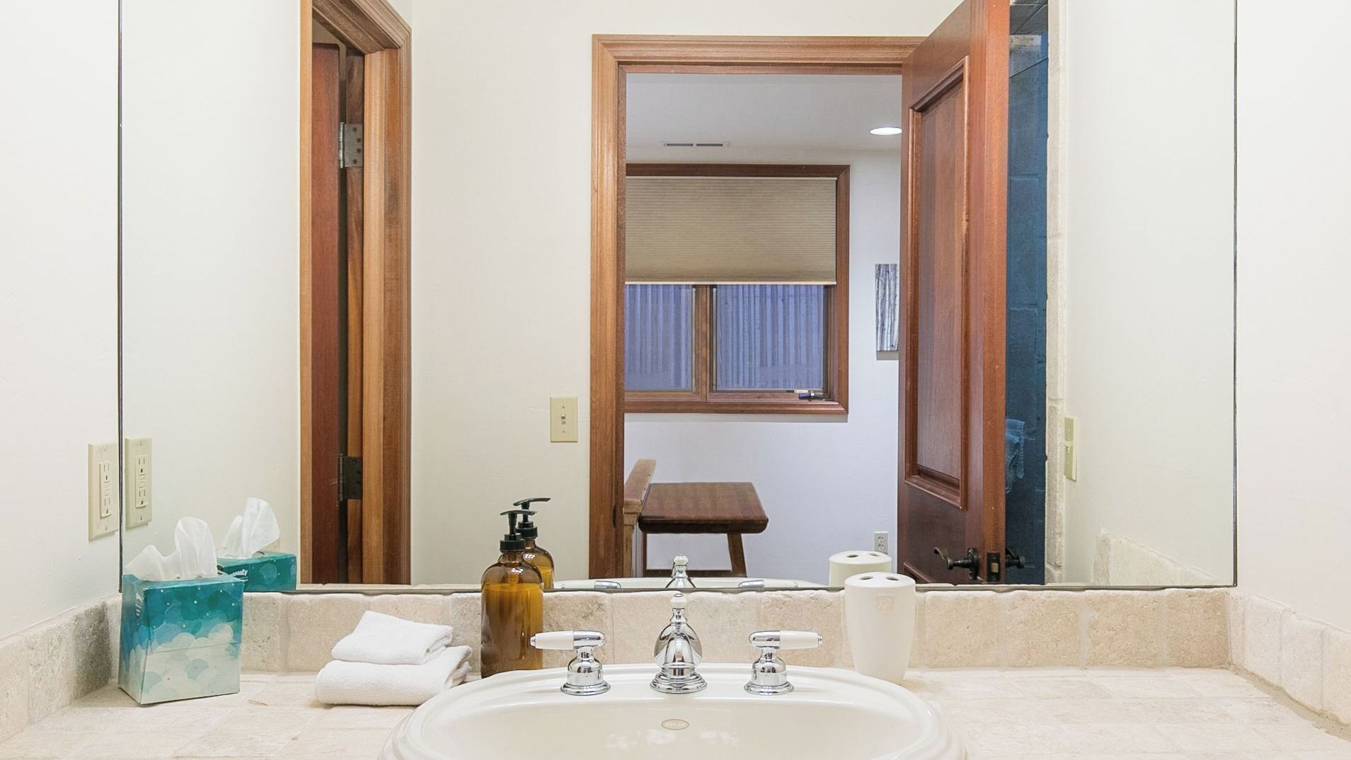 A bathroom with a sink, mirror, and toiletries.