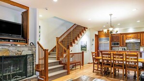 A spacious living area with a fireplace, wooden staircase, and a dining area with wooden chairs and a table. - Pacific Street Townhome 514b by Avantstay Cute Townhouse in the Heart of Telluride! (Telluride)