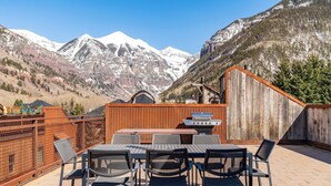 An outdoor patio with a table and chairs, a barbecue grill, and a wooden fence. - Ghostriders 10 by Avantstay Penthouse Suite w/ Large Patio & Mountain Views! (Telluride)