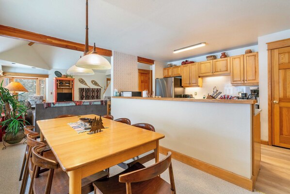 Una cocina moderna con armarios de madera, una isla central y un comedor con mesa y sillas de madera.
