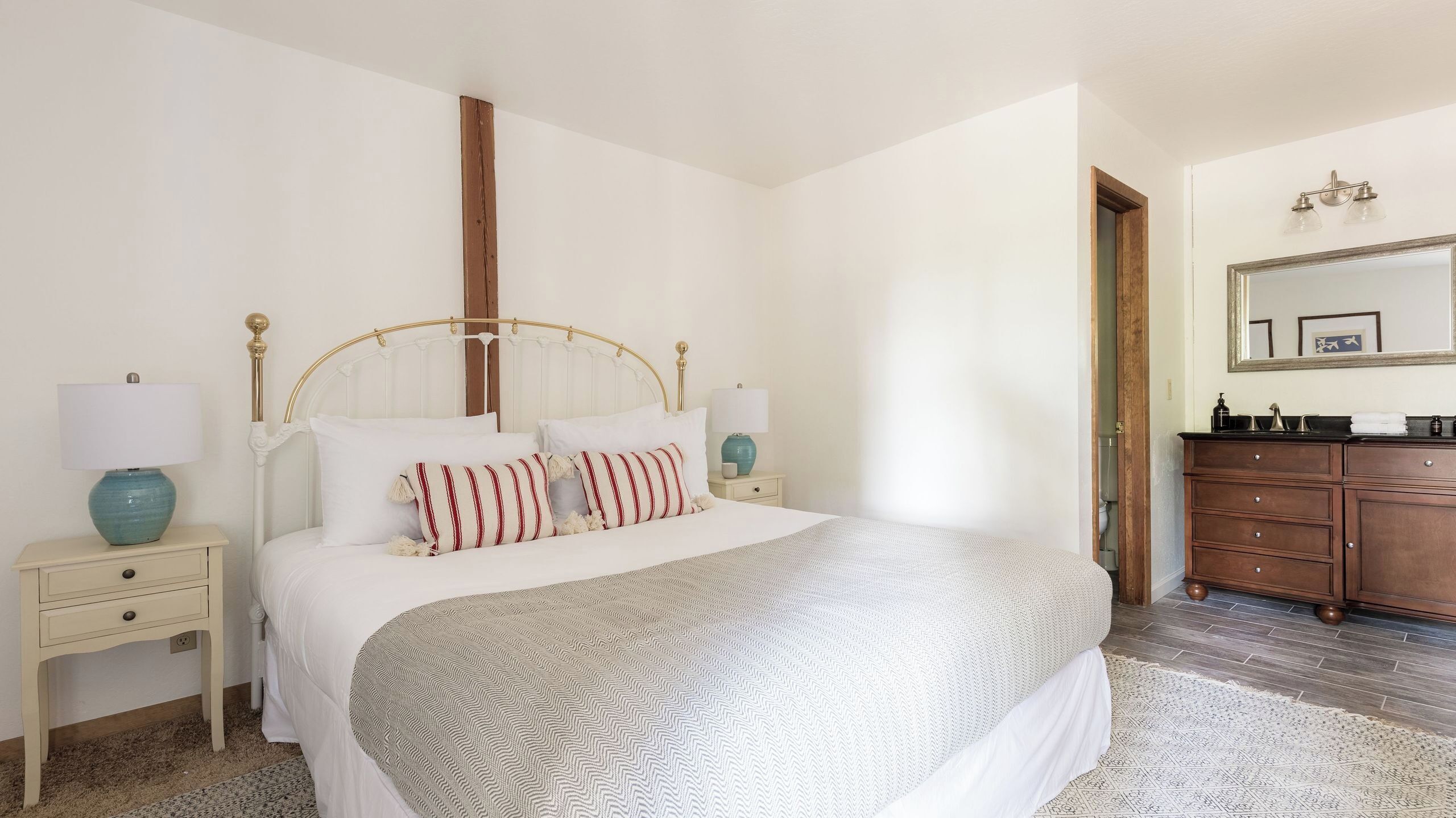 A bedroom with a bed, nightstands, a dresser, a mirror, and a door.