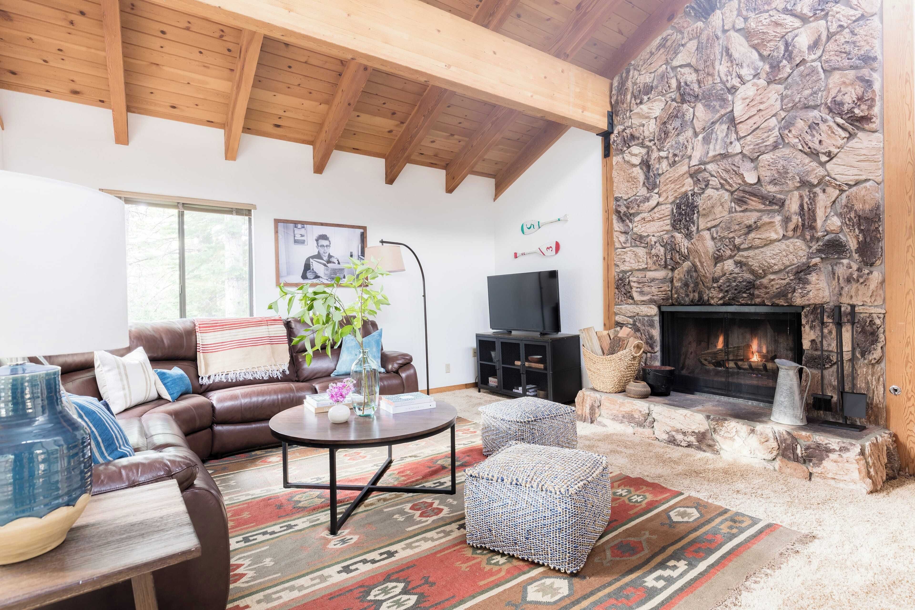 A cozy living room with a stone fireplace, leather sofa, and a television.