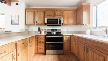 Una cocina con armarios de madera, una estufa de acero inoxidable, un microondas y un lavamanos.