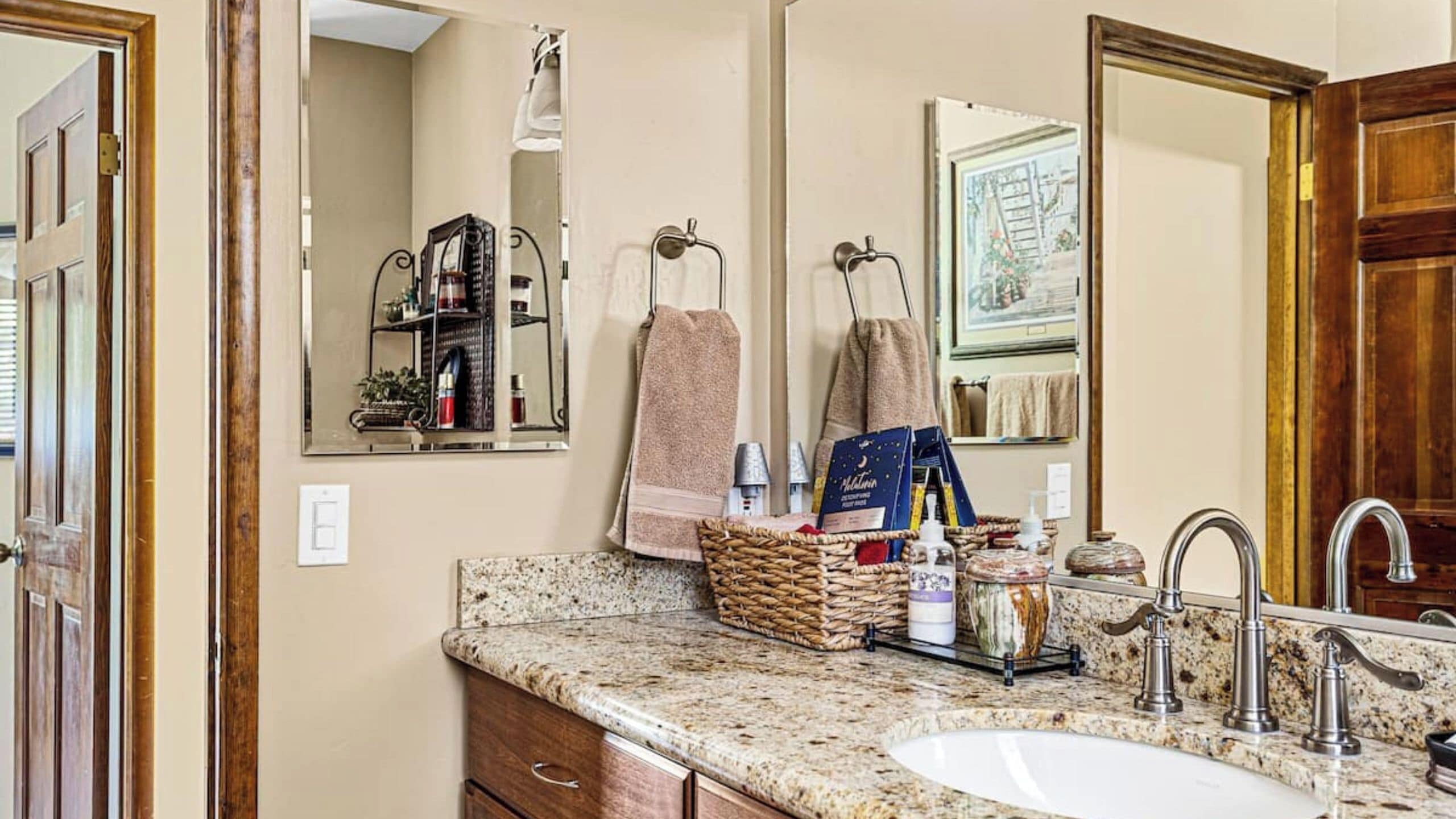 A bathroom with a granite countertop, a sink, a mirror, and a towel rack.
