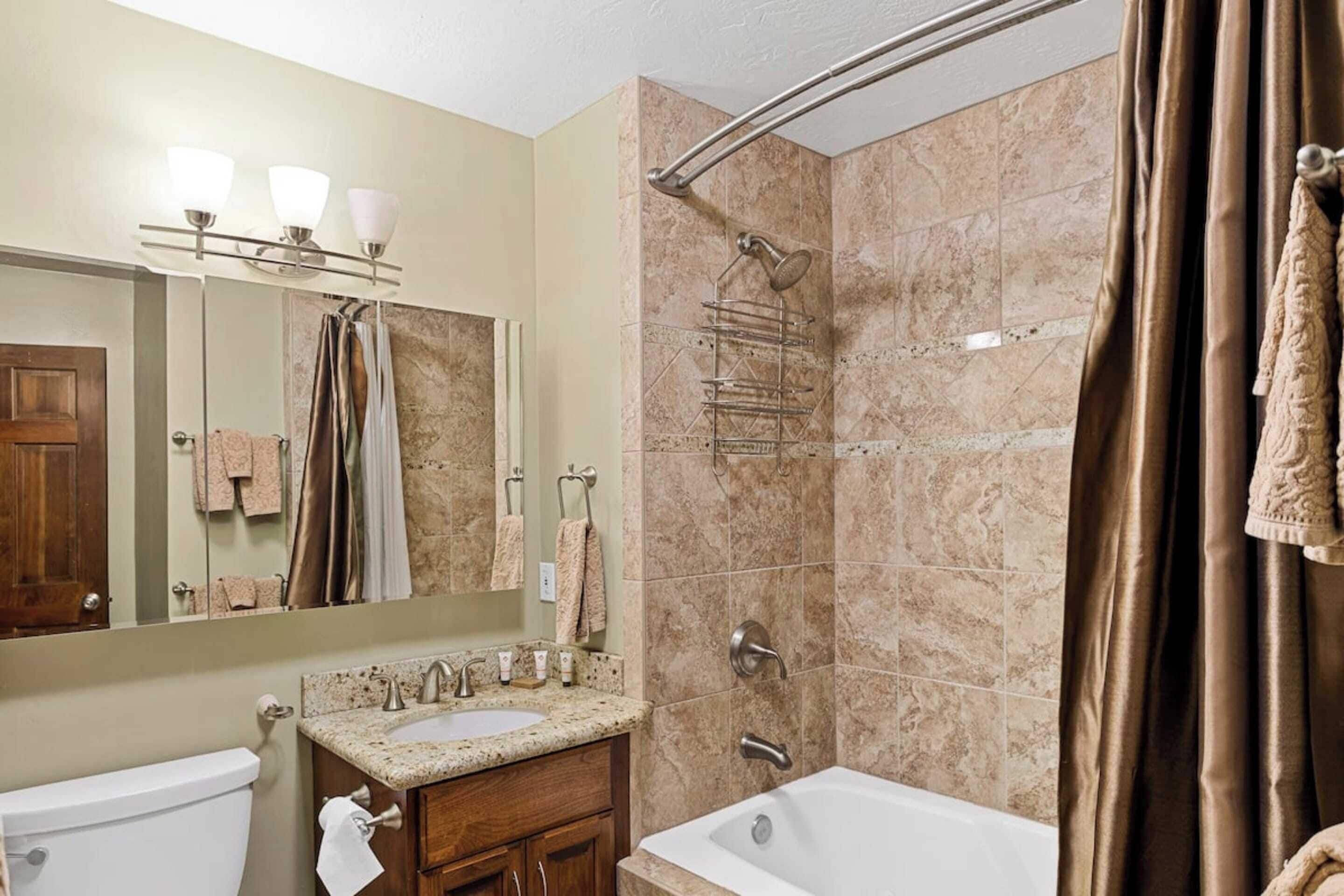 A bathroom with a sink, mirror, and shower.