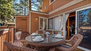 Eine Holzterrasse mit Korbmöbeln und einem Glastisch, gedeckt für ein Essen.