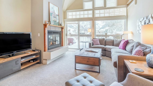 A spacious living room with a large flat-screen TV, a fireplace, a sofa, and a coffee table. - Etta Place Too 113 by Avantstay Close to Town & The Slopes! In Complex w/ Communal Pool & Hot Tub (Telluride)