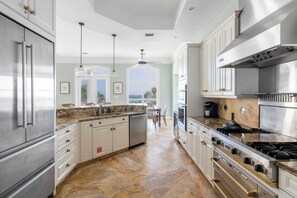 Enjoy cooking in this well-equipped kitchen with a refrigerator, dishwasher, and stove, set against a view of the outdoors.