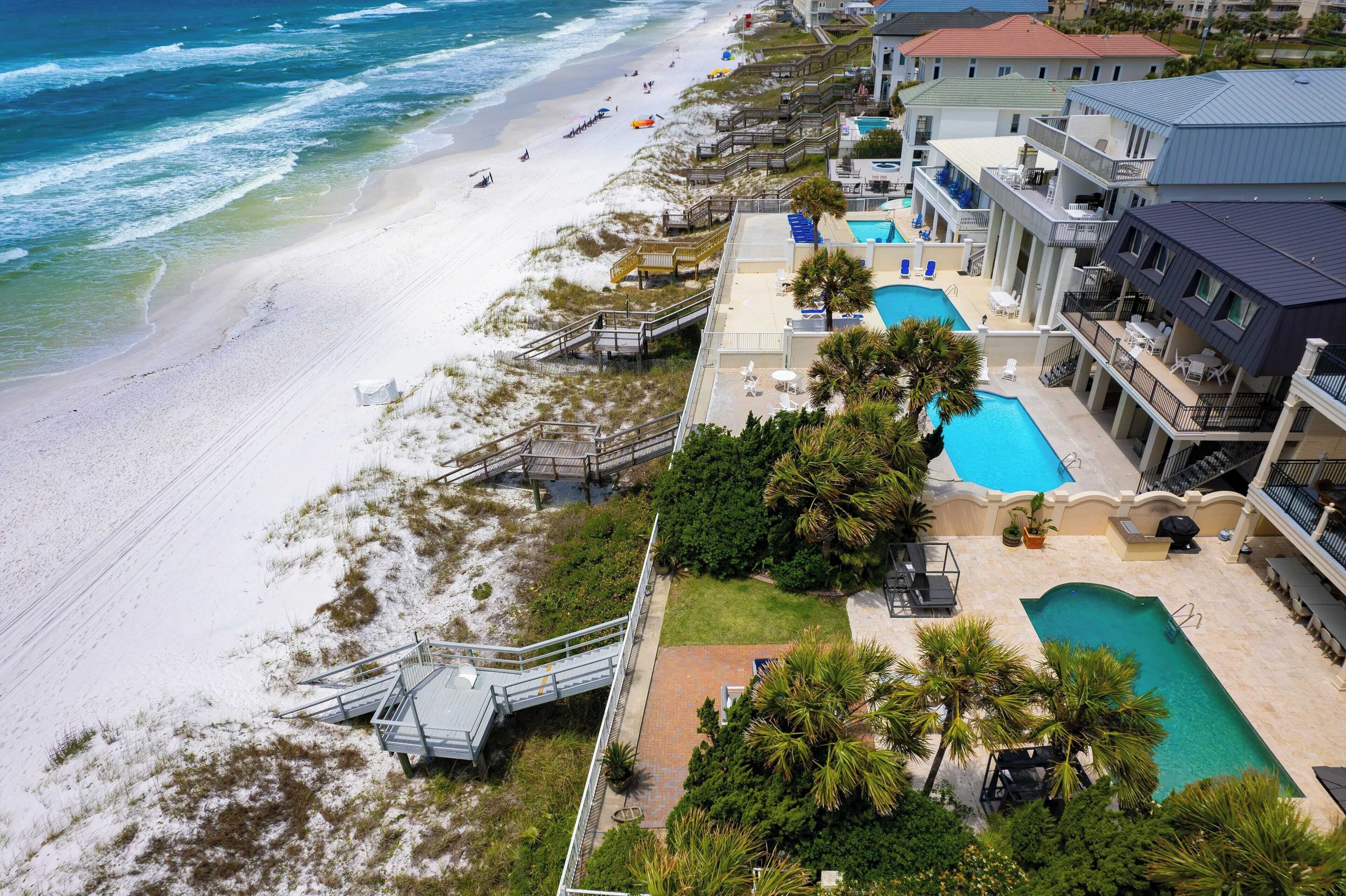 A beachfront hotel with a swimming pool, beach access, and a staircase leading to the beach.