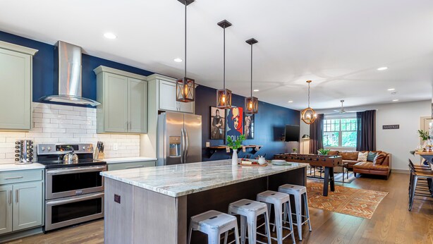 A modern kitchen with stainless steel appliances, a central island with bar stools, and a dining area with a brown leather sofa. - Waverly by Avantstay Nashville-inspired Townhome w/ Luxury Kitchen, Pool Table (Nashville)
