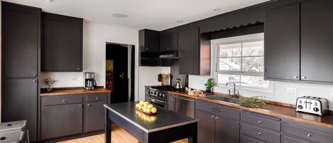 Une cuisine moderne avec des meubles de couleur sombre, un plan de travail en bois et un îlot central.