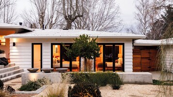 Una casa moderna con tejado nevado, ventanas grandes y un interior bien iluminado.