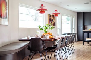 Un comedor moderno con una mesa larga, varias sillas y luces colgantes.
