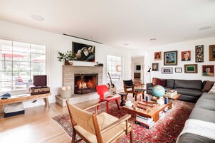 Una sala de estar con chimenea, un sofá, una mesa de centro y una silla roja.