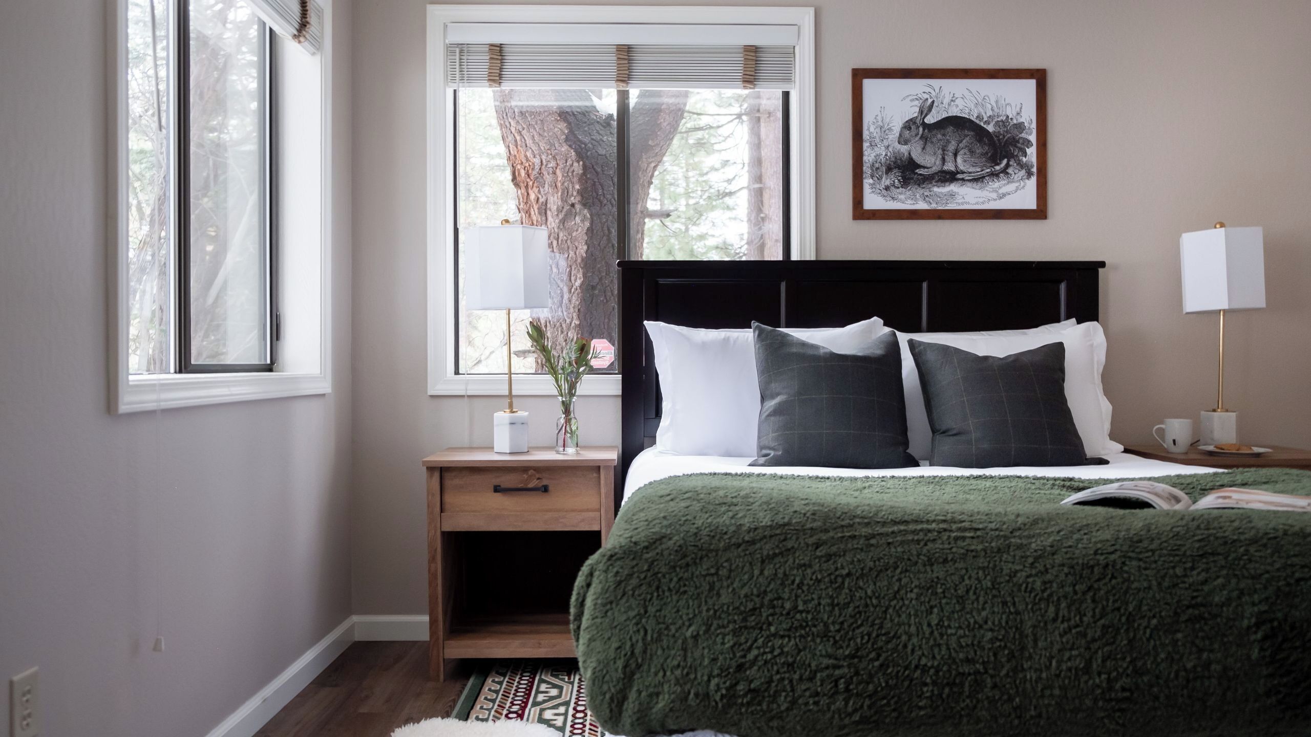 A bedroom with a bed, nightstand, lamp, and a framed picture on the wall.