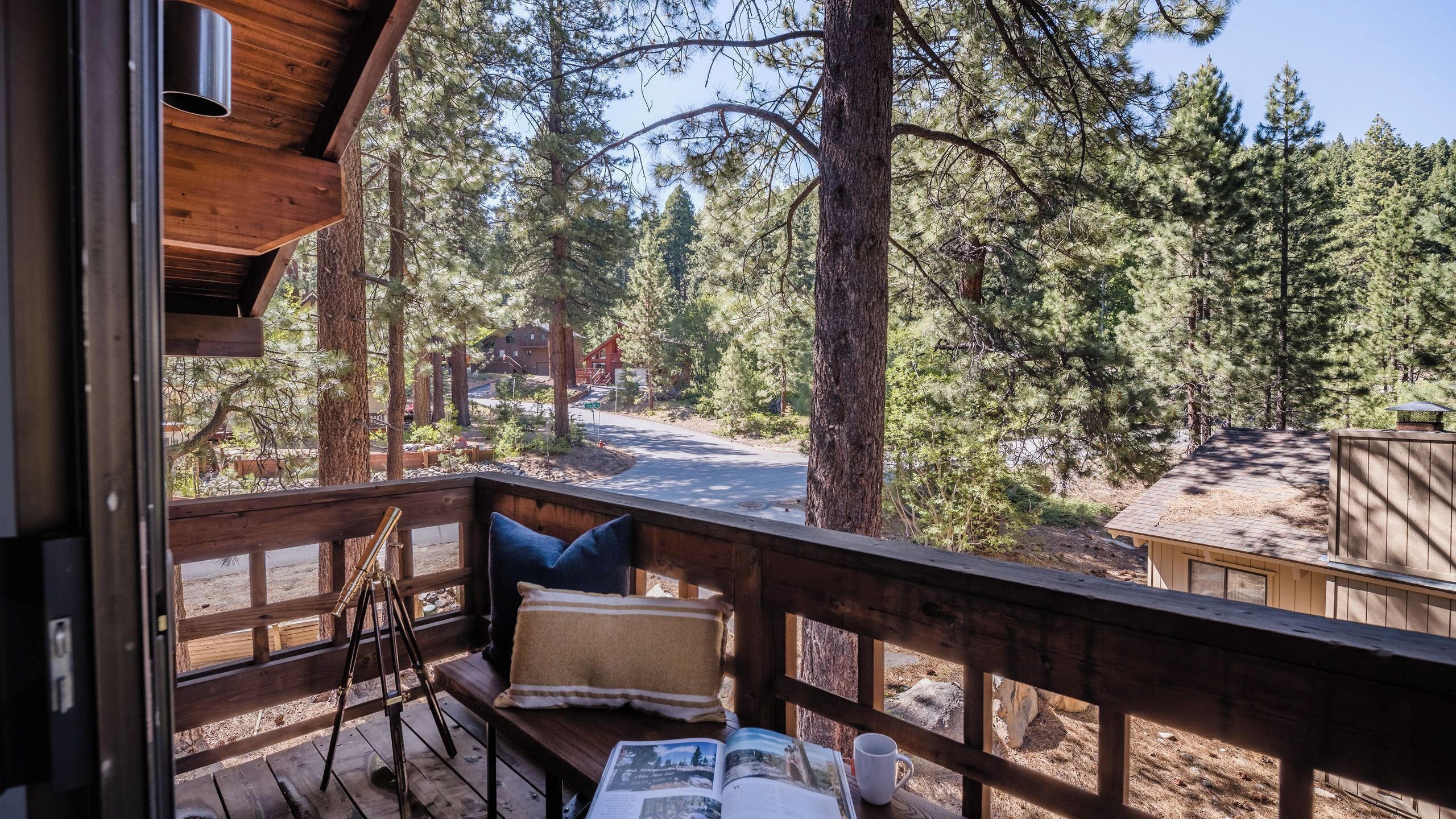 A wooden deck with a bench, a camera on a tripod, and a book open on the bench.