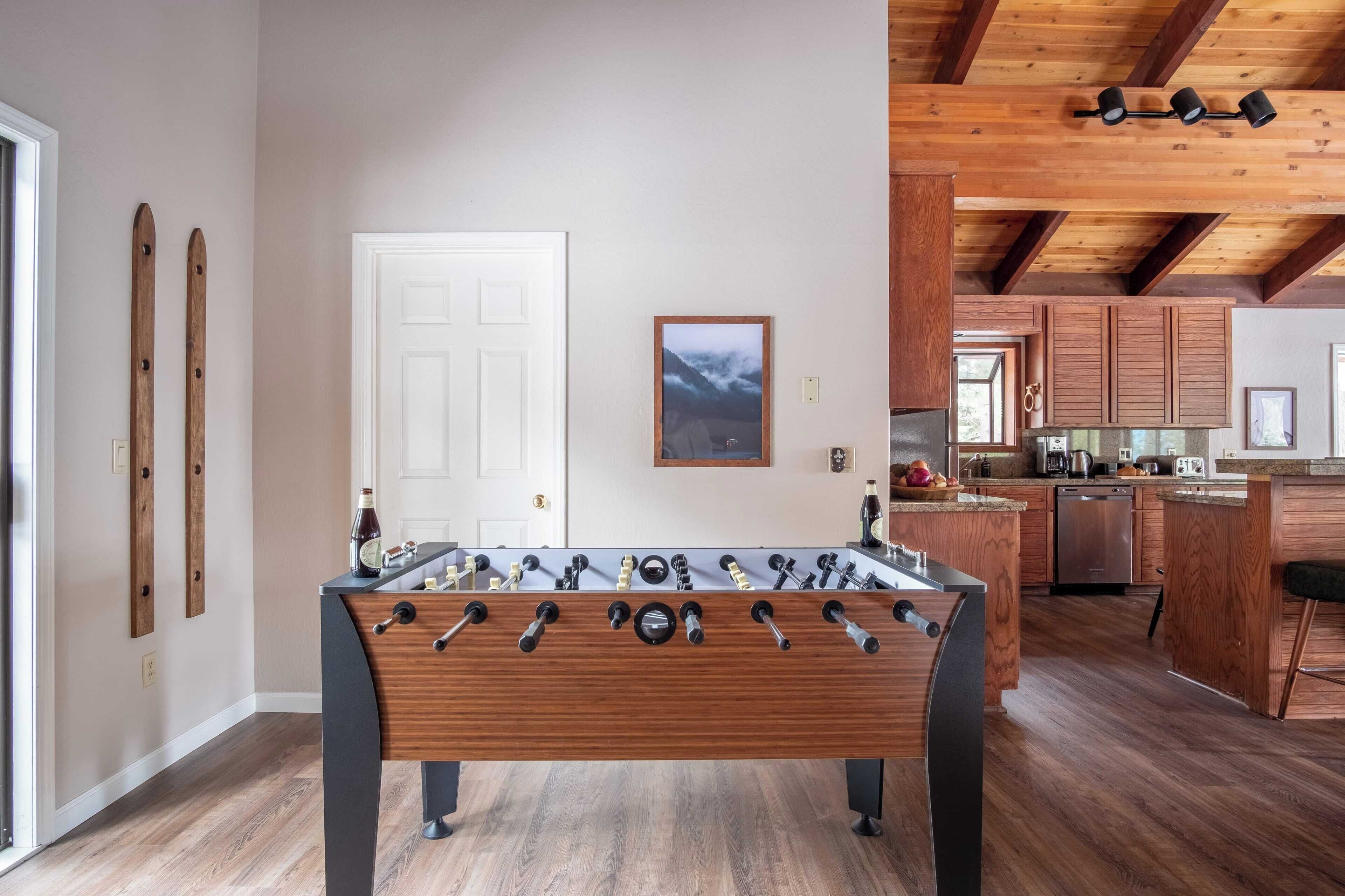 A modern kitchen with wooden cabinets, a central island, and a foosball table.