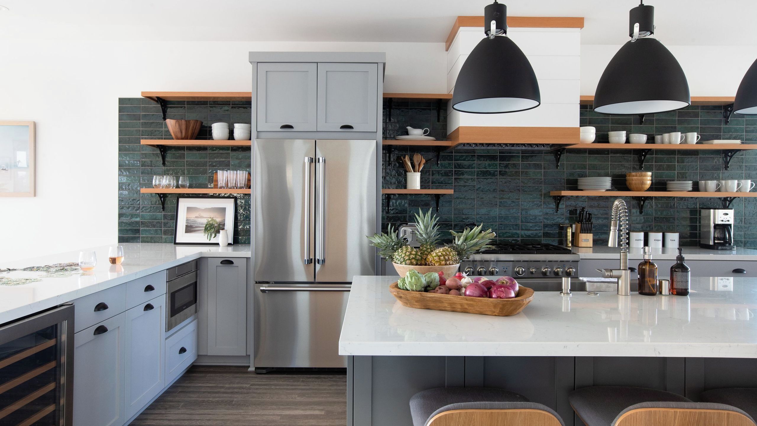 Una cucina moderna con isola centrale, elettrodomestici in acciaio inossidabile e mensole in legno.