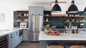 Una cocina moderna con una isla central, electrodomésticos de acero inoxidable y estantes de madera.