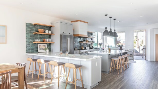 Una cucina moderna con isola centrale, sgabelli da bar e zona pranzo con tavolo in legno.