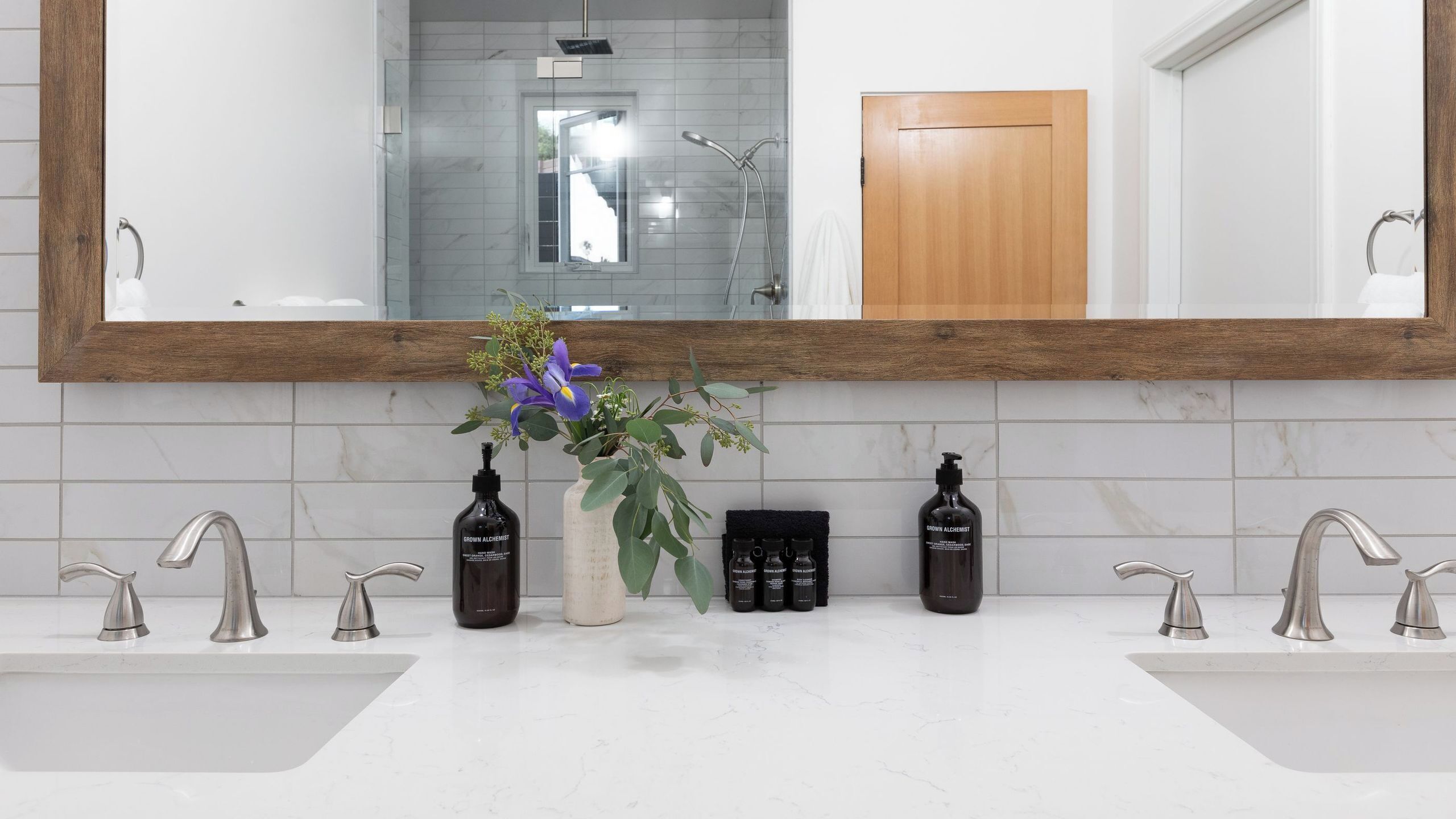A bathroom with two sinks, a large mirror, and a shower.