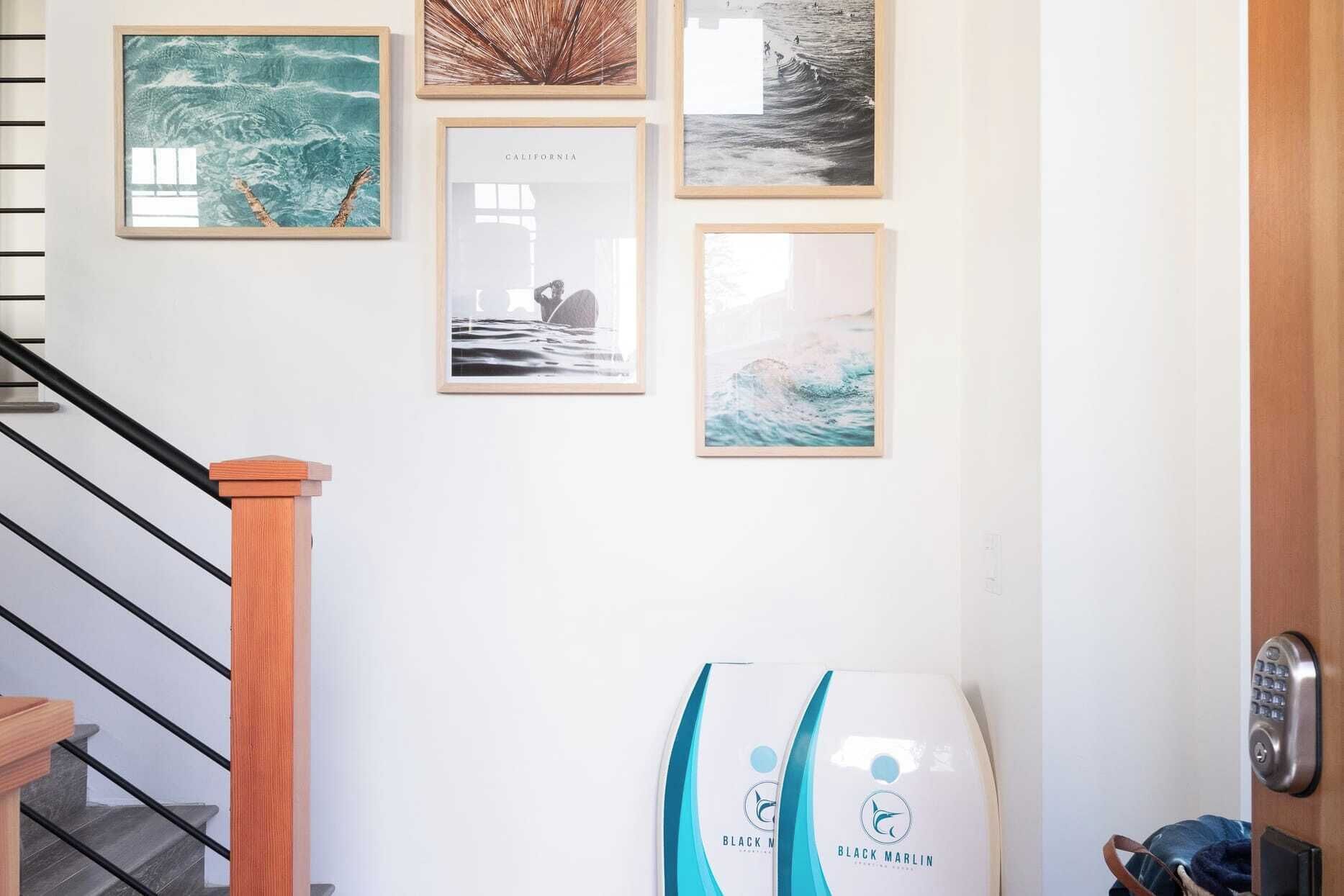 A staircase with wooden handrails and a wall with framed pictures of ocean scenes.