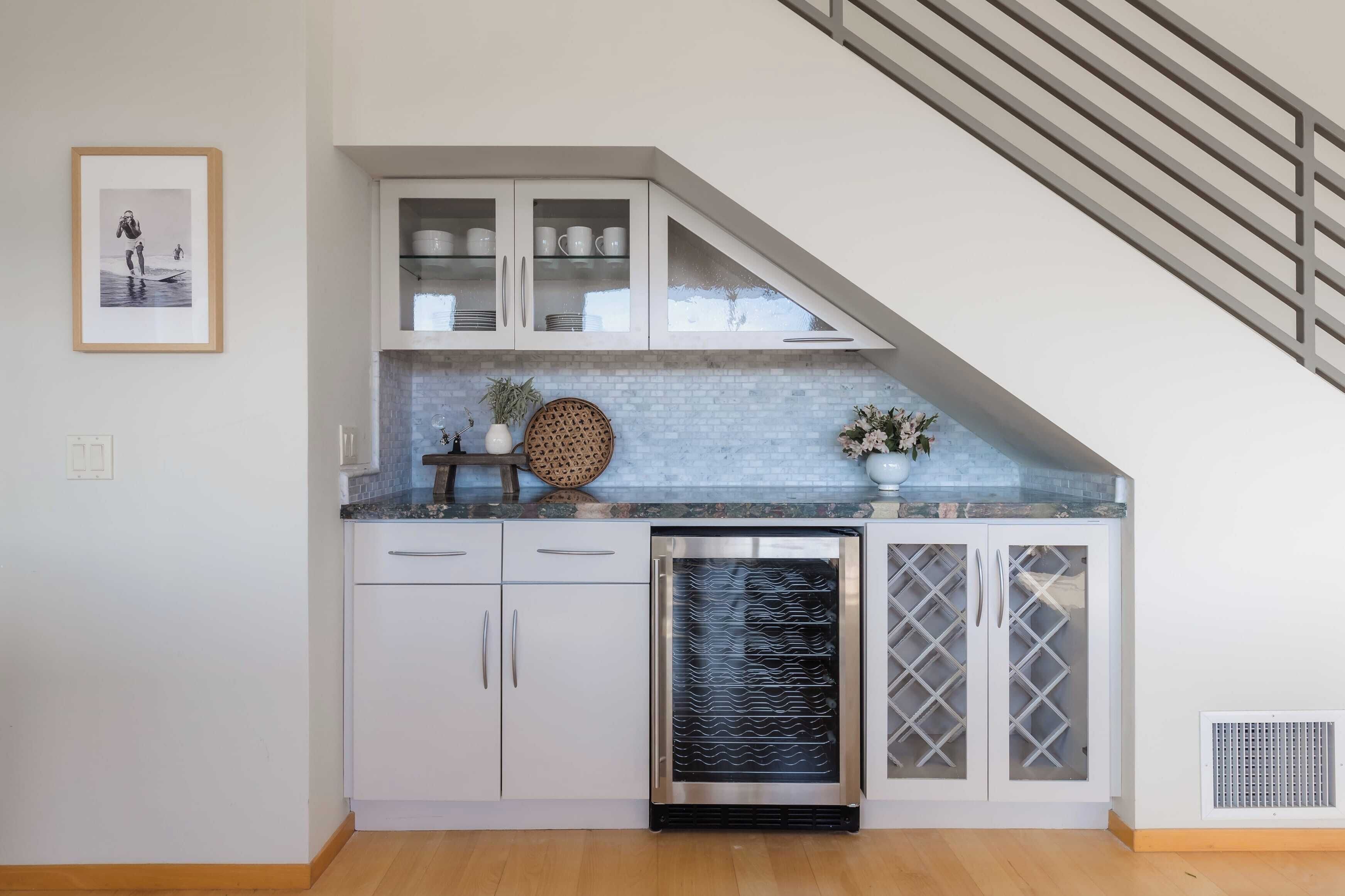 Cocina con armarios blancos, un enfriador de vino de acero inoxidable y salpicadero de azulejos.