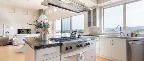 A modern kitchen with a large island, stainless steel appliances, and a view of the outdoors.