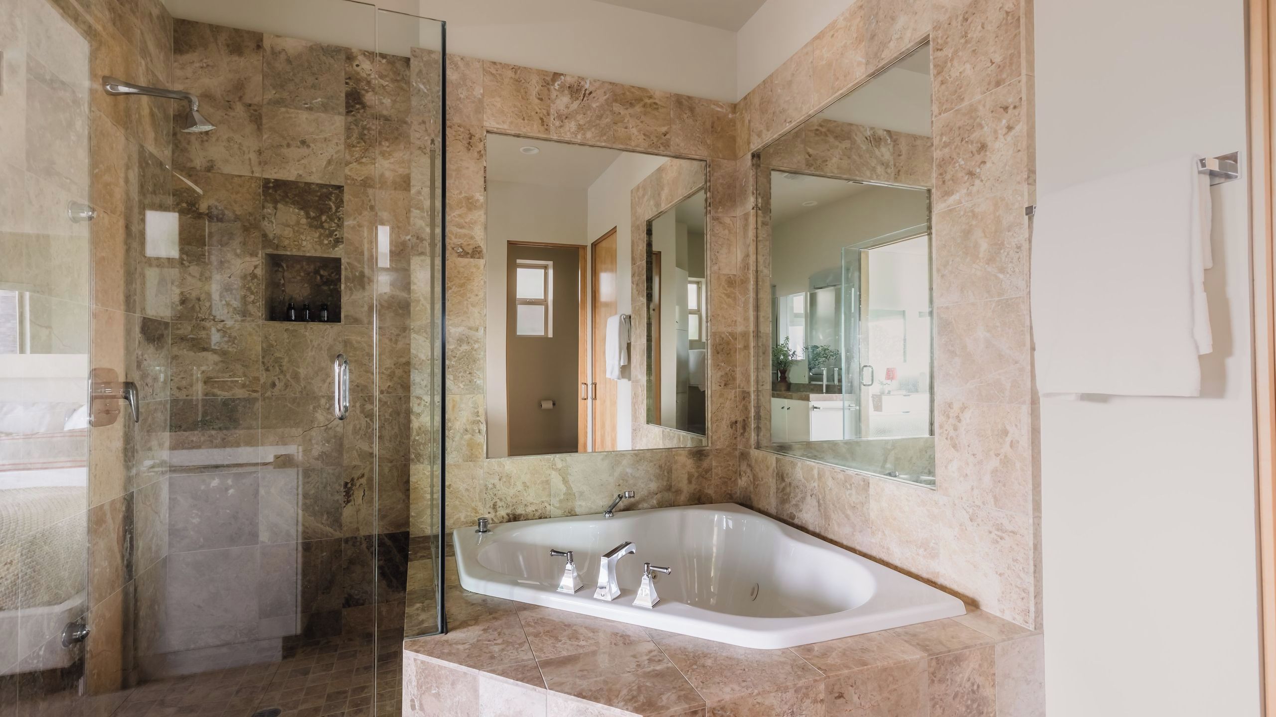 A bathroom with a glass shower enclosure, a freestanding bathtub, and a large mirror.