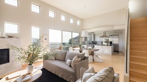 A spacious living area with a sofa, a dining table, and a kitchen in the background. - Seascape by Avantstay Spacious Contemporary Oasis in Del Mar (Del Mar)