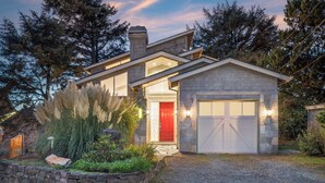 A modern house with a stone facade, a red door, and a garage. - Villa Manzanita by Avantstay Hot Tub, 1 Block to Beach/town, Chef's Kitchen (Manzanita)